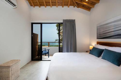 a bedroom with a large bed and a balcony at Villa Kañik - Luxury Retreat with Concierge Services in Dominical