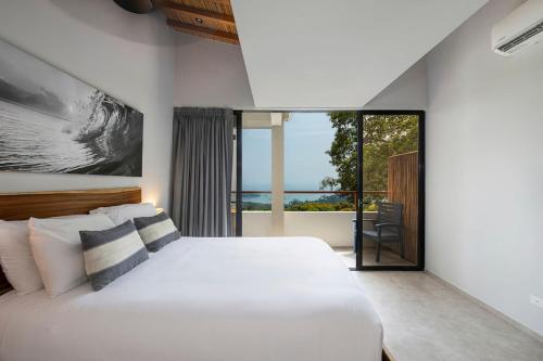 a bedroom with a white bed and a large window at Villa Kañik - Luxury Retreat with Concierge Services in Dominical