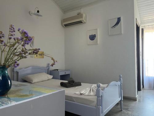 a white bedroom with a bed and a vase of flowers at Potokaki Beachfront Hotel in Pythagoreio