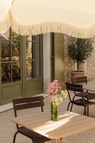 une table avec un vase de fleurs sur une terrasse dans l'établissement Mas de l'Etoile, à Aureille
