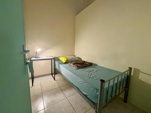 a small bedroom with a bed and a side table at Backpacker's Bed - No Parking in Abu Dhabi