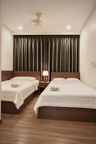a bedroom with two beds and a window with curtains at Ngọc Hoa - Nam Hội An Hotel in Thăng Bình