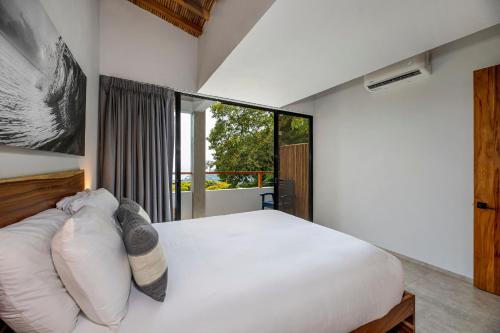 a bedroom with a white bed and a large window at Villa Kañik - Luxury Retreat with Concierge Services in Dominical
