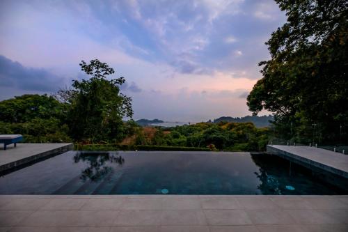 a swimming pool with a sunset in the background at Villa Kañik - Luxury Retreat with Concierge Services in Dominical