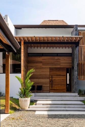 a house with a wooden door and a porch at Villa Kañik - Luxury Retreat with Concierge Services in Dominical
