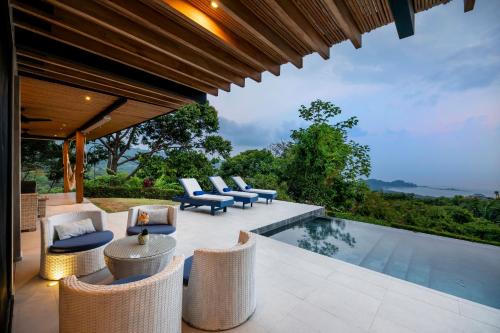 an outdoor patio with chairs and a swimming pool at Villa Kañik - Luxury Retreat with Concierge Services in Dominical