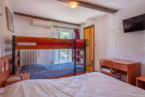 a bedroom with two bunk beds and a desk at Logis Hôtel Beauséjour in Berre-les Alpes