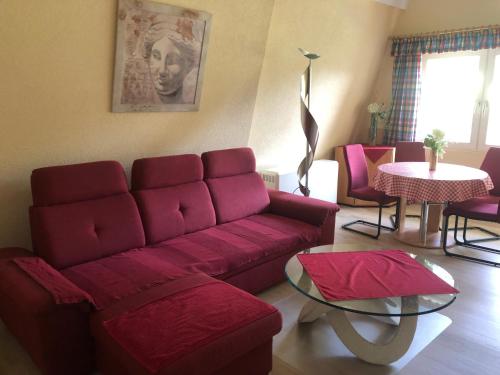 Una sala de estar con un sofá rojo y una mesa. en Haus Dachsberg Todtmoos, en Todtmoos