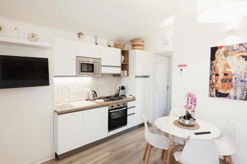 Una cocina con gabinetes blancos y una mesa con sillas. en Casa Gisa, en Olbia