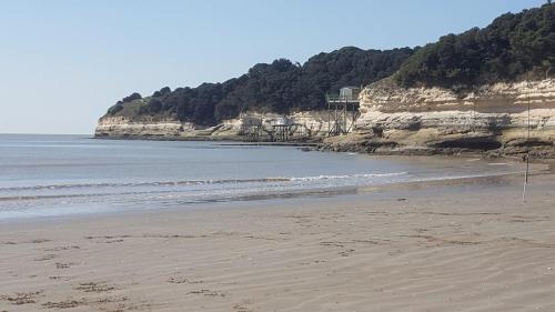a beach with the ocean and a rocky shore at APPARTEMENT PRES DE ROYAN 7 MINUTES MER CONFORT CALME rdc espace détente jardin in Sémussac