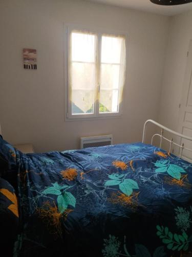 a bed with a blue blanket with plants on it at APPARTEMENT PRES DE ROYAN 7 MINUTES MER CONFORT CALME rdc espace détente jardin in Sémussac