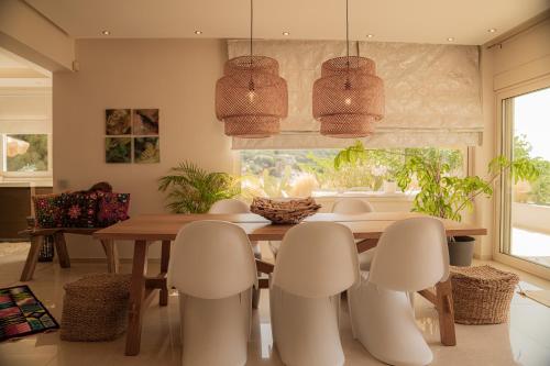 a dining room with a wooden table and chairs at Aerides Luxury Villa in Paleo Tsifliki
