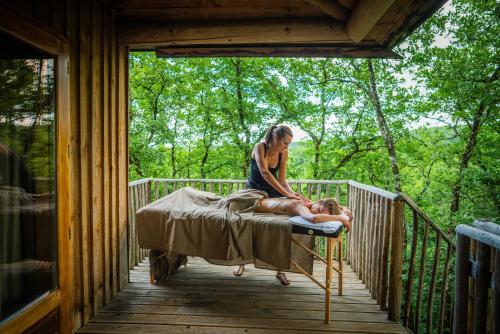 a woman sitting on a bed on a porch with a man at Hébergement insolite en Dordogne in Saint-Amand-de-Coly