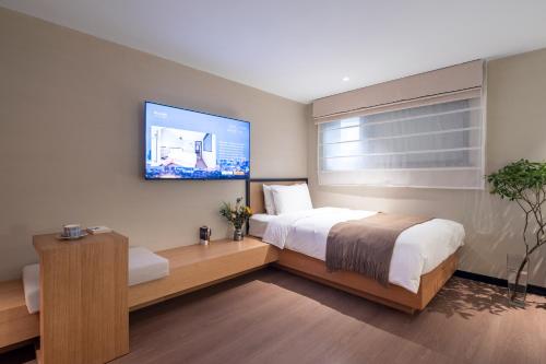 a bedroom with a bed and a tv on the wall at Beijing Tangfu Nanluoguxiang Tian an Men Lama Temple San Li Tun Snack Street Hotel,Free Laundry Dry Service and Free Afternoon Tea &professional Free Tour Ticket Service with English Speaking Staff in Beijing