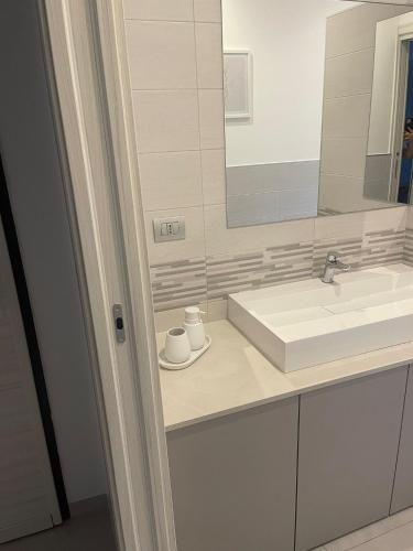 a white bathroom with a sink and a mirror at Casa Kennedy Apartments in Centallo