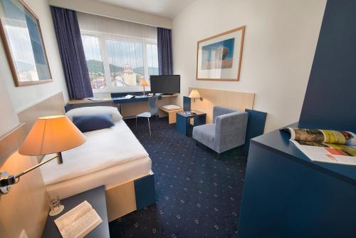 a hotel room with a bedroom with a bed and a desk at Hotel Grand Litava Beroun in Beroun