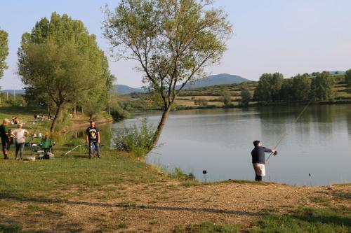 a group of people standing by a lake fishing at E-Tekergők Háza in Bükkzsérc
