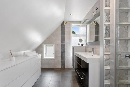 a white bathroom with a sink and a mirror at Large apartment with 5 bedrooms, 2 bathrooms and roof terrace in Ålesund