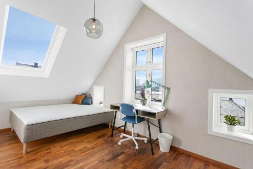 a bedroom with a bed and a desk and windows at Large apartment with 5 bedrooms, 2 bathrooms and roof terrace in Ålesund