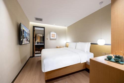 a hotel room with a large white bed and a desk at Beijing Tangfu Nanluoguxiang Tian an Men Lama Temple San Li Tun Snack Street Hotel,Free Laundry Dry Service and Free Afternoon Tea &professional Free Tour Ticket Service with English Speaking Staff in Beijing