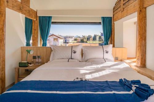 a bedroom with a large bed with a large window at 玉龙白沙普宿客栈 in Lijiang