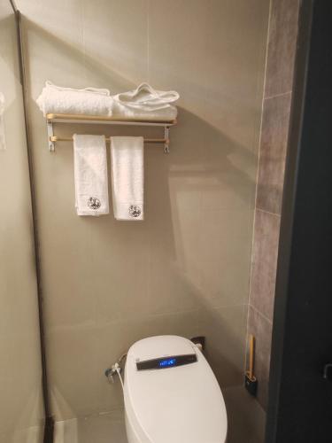 a small bathroom with a toilet and towels at 玉龙白沙普宿客栈 in Lijiang