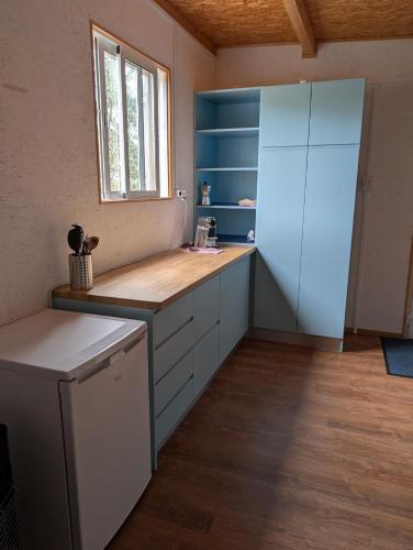 a large kitchen with blue cabinets and a window at Bungalow Quinta Sete Charós in Nisa
