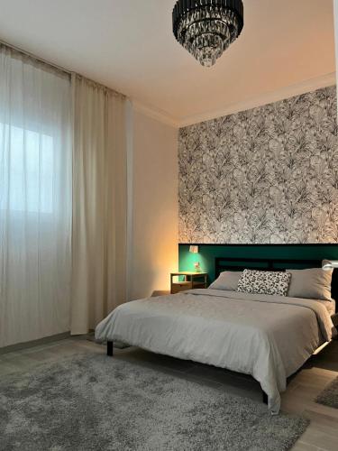 a bedroom with a large bed and a chandelier at The Pearl Suite - your stylish cozy and modern flat,in the heart of South Tenerife,just 3 minutes from beach and natural pools in Alcalá