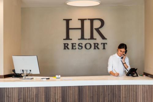 a man talking on a phone at a reception desk at HR Resort in Senigallia