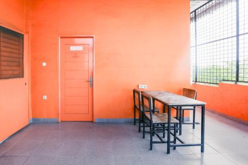 a table and chairs in a room with an orange wall at RedDoorz at Seindo Hotel Medan in Sunggal