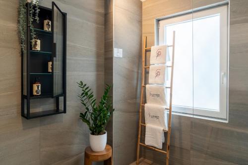 łazienka z półką na ręczniki i rośliną w obiekcie Garment District Suites w Atenach