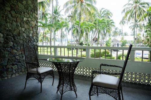 a balcony with a table and chairs and palm trees at Waterfront Insular Hotel Davao in Davao City