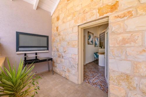 a living room with a stone wall and a flat screen tv at הזהר הצפוני in Rosh Pinna