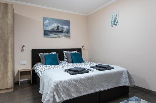 a bedroom with a large bed with blue pillows at Lucsony Apartman in Mosonmagyaróvár
