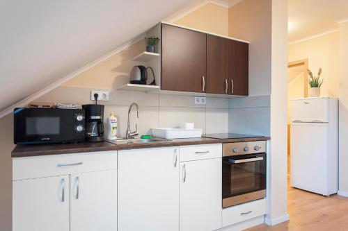 a kitchen with white cabinets and a white refrigerator at Lucsony Apartman in Mosonmagyaróvár