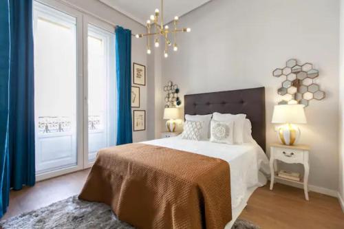 a white bedroom with a large bed and a chandelier at My City Home- Lujoso Apartamento en Sol in Madrid