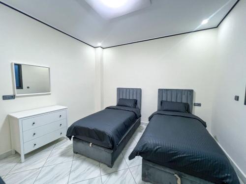 a bedroom with two beds and a dresser and a mirror at Appartement Alhoceima in Imejoudene