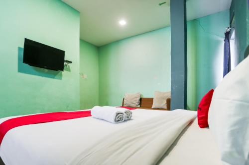 a bedroom with a bed with a tv on the wall at RedDoorz at Sentosa Jaya Helvetia in Pulauberayan
