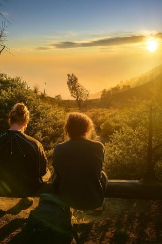 two people sitting on a bench watching the sunset at Nio Homestay and Tour in Licin