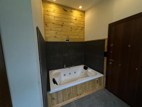 a bath tub in a bathroom with a wooden wall at Ayder Serender otel in Çamlıhemşin