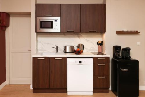 La cuisine est équipée d'un réfrigérateur blanc et d'un four micro-ondes. dans l'établissement Tèrra d'Automne by Rahault ConciergerieDameCarcas, à Carcassonne