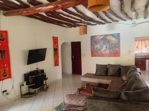 a living room with a couch and a tv at HIDEOUT Villa in Ukunda