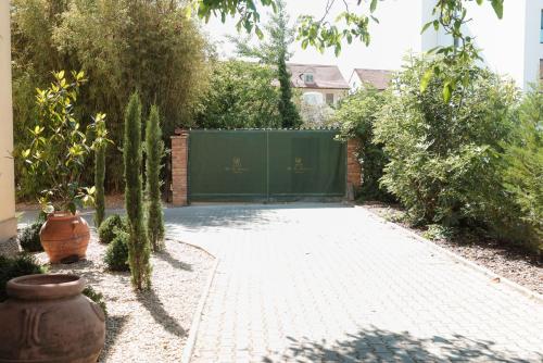 a driveway with a green gate in a garden at Hotel La Residenza in Timişoara