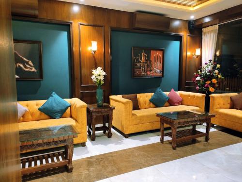 a living room with yellow couches and blue walls at Hotel Chaitanya Executive in Māngvādi