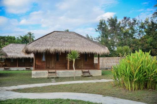 a small hut with a straw roof and two benches at Beranda Ecolodge in Gili Air