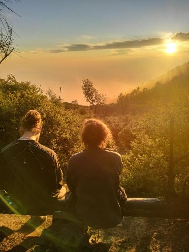 a man and woman sitting on a bench watching the sunset at Nio Homestay and Tour in Licin