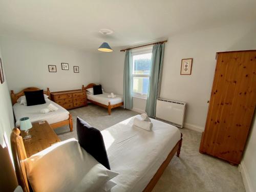 a bedroom with two beds and a window at Killick Cottage in Sidmouth