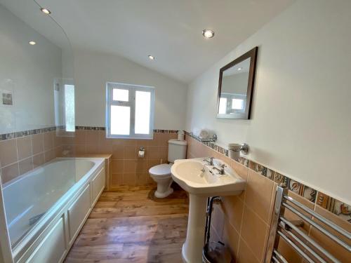 a bathroom with a tub and a toilet and a sink at Killick Cottage in Sidmouth