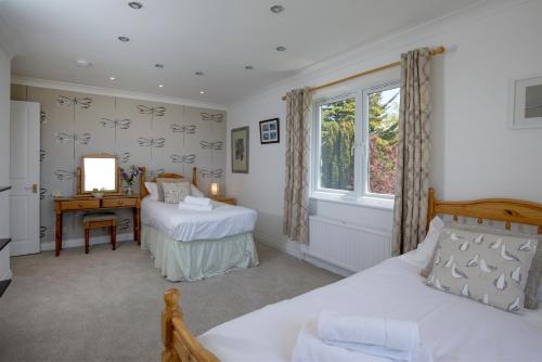 埃克斯茅斯Lark Rise的一间卧室，有两张床、一张书桌和一扇窗户