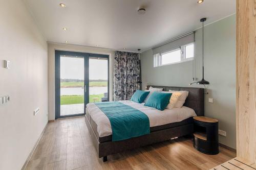 a bedroom with a large bed and a large window at Wellness aan de Vecht - Begane grond by Droomvilla in Dalfsen